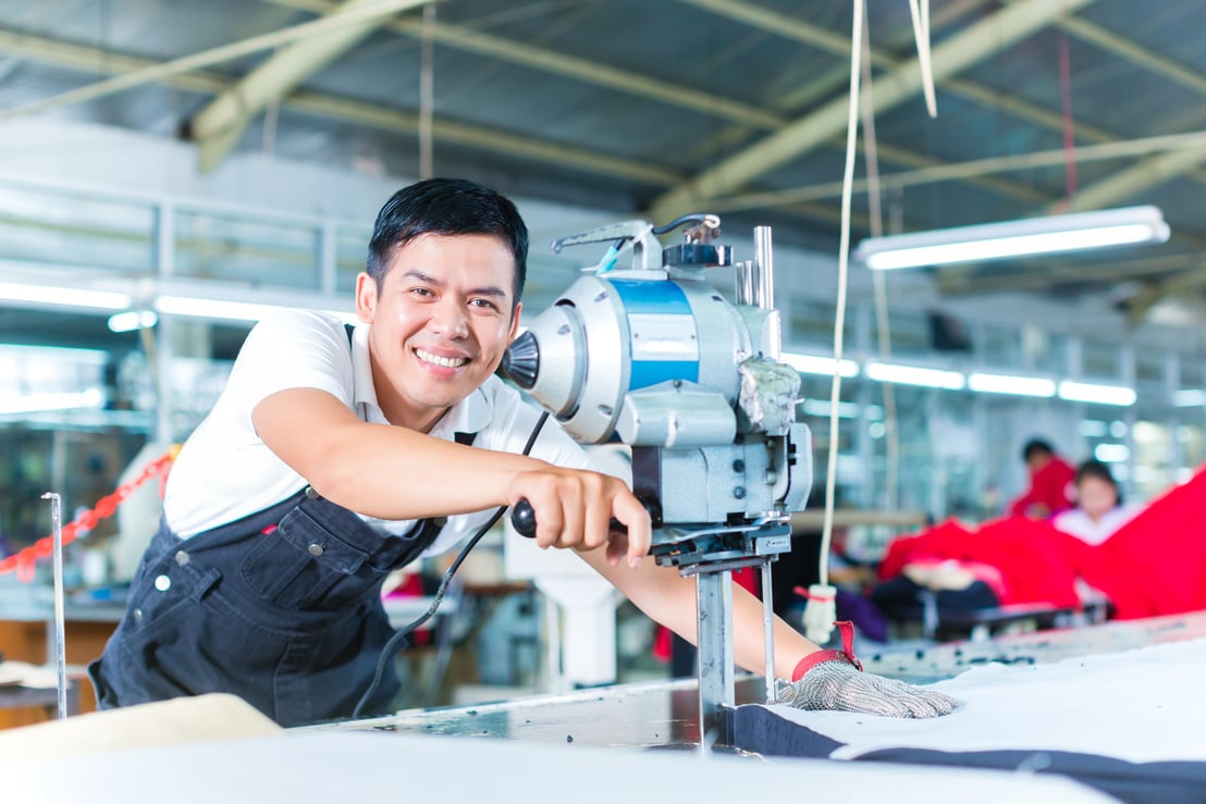 Asian Worker Using a Machine in a Factory