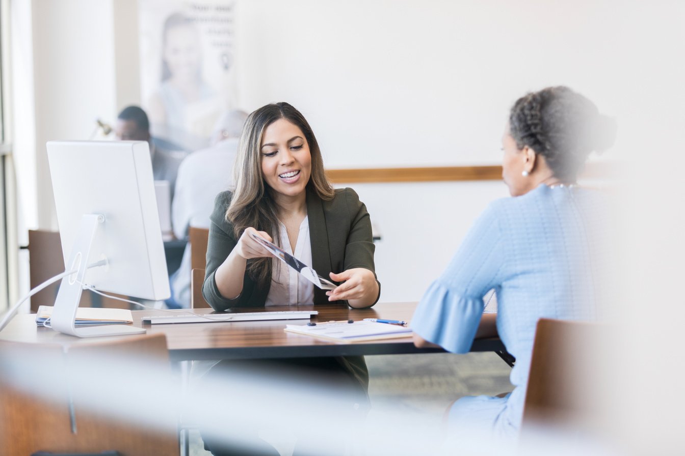 Mid adult loan officer helps mature customer select loan